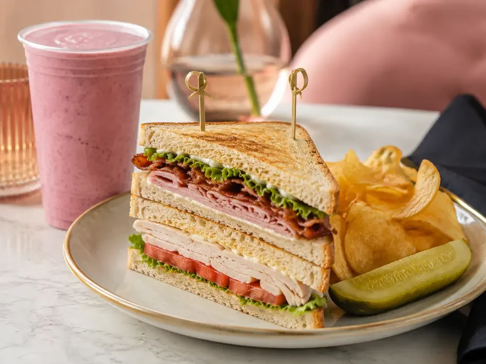 Crave double-decker sourdough club with turkey, ham, bacon, lettuce, tomato, chips, pickle and smoothie